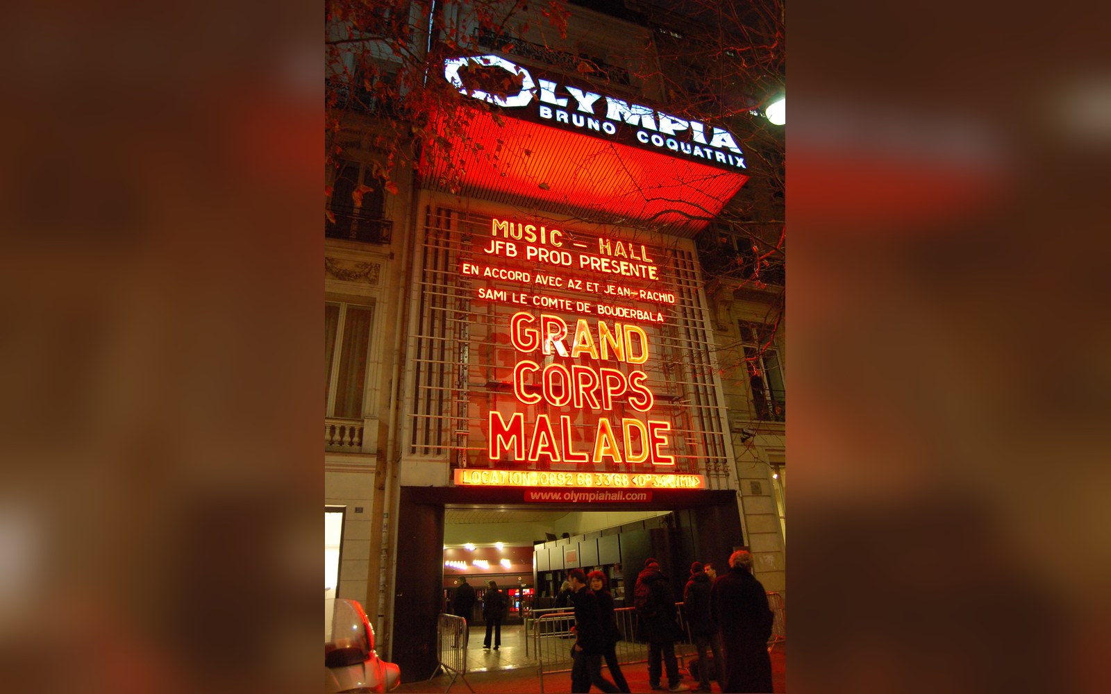 Olympia frontage lit at night with people on the pavement