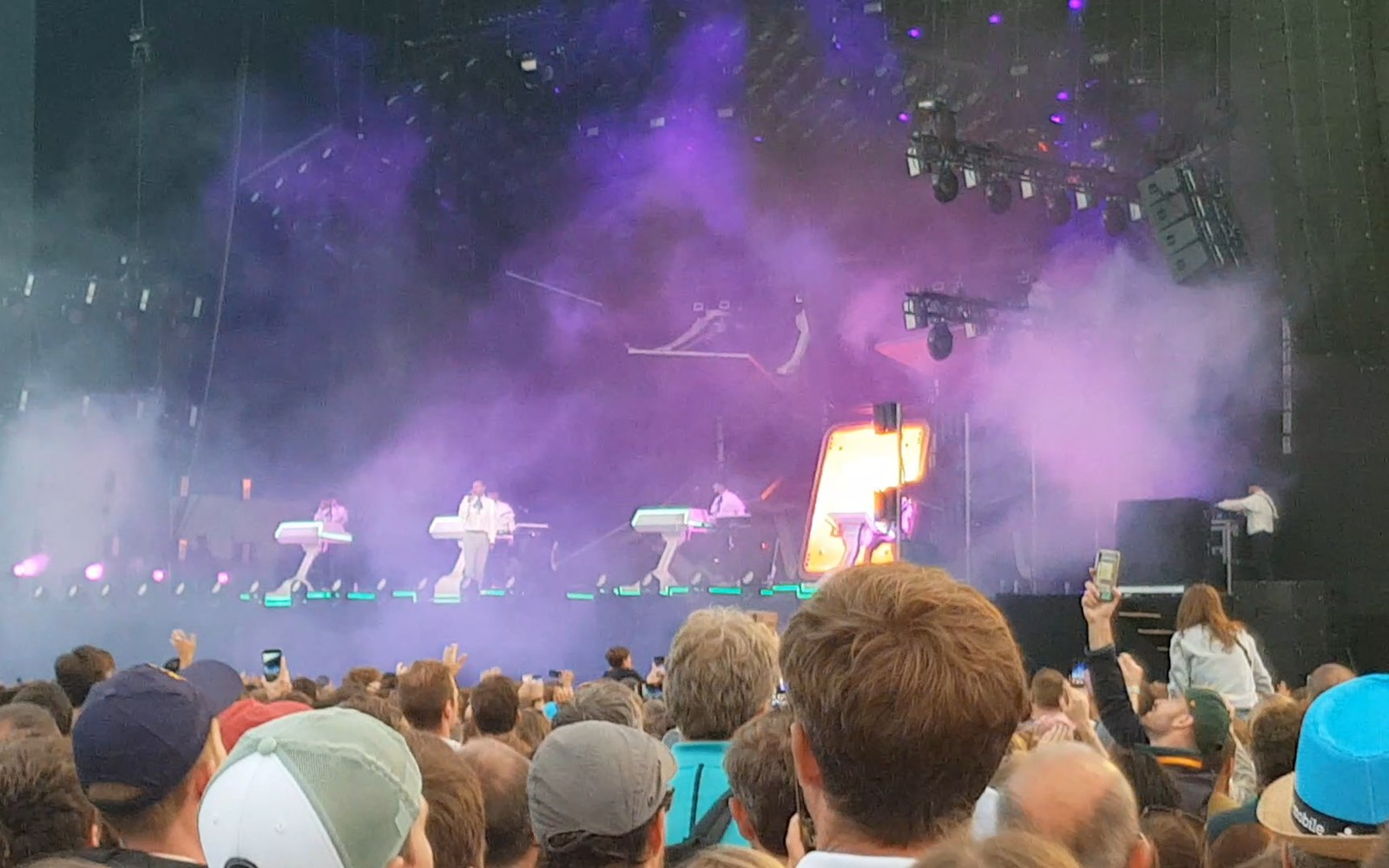 Crowd watches Stromae perform on a smoke-filled stage bathed in purple festival lighting